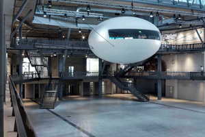  In der dreigeschossigen „Arena für Nachhaltigkeit“ schwebt ein „Cocoon“, der über Brücken mit den einzelnen Ausstellungsebenen verbunden ist.  